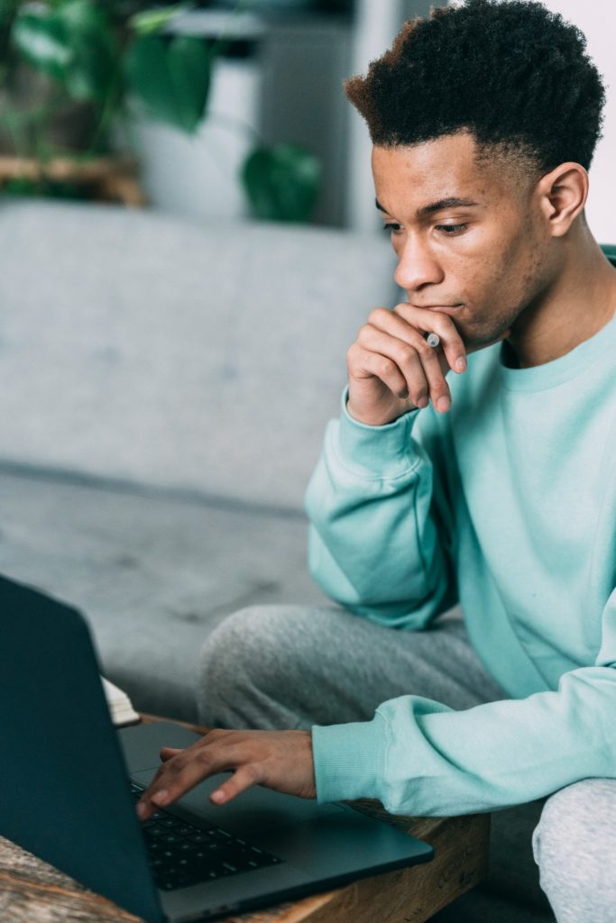 man looking lost in thought as he uses laptop