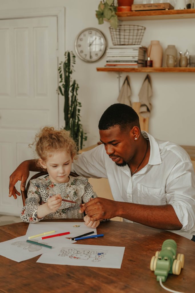 Father and daughter coloring at kitchen table