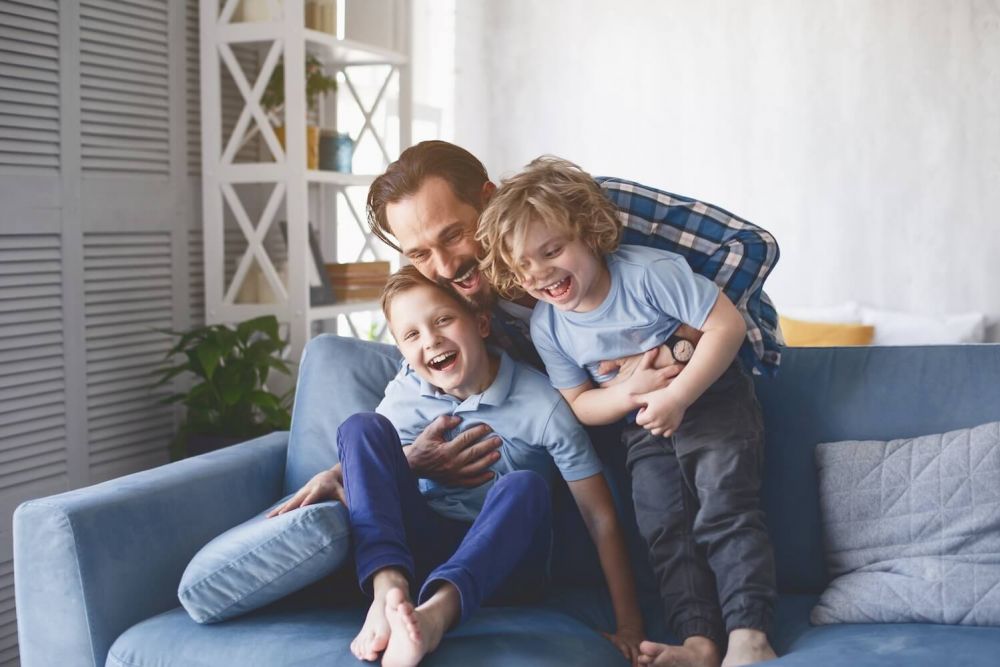 father playing with his kids on couch