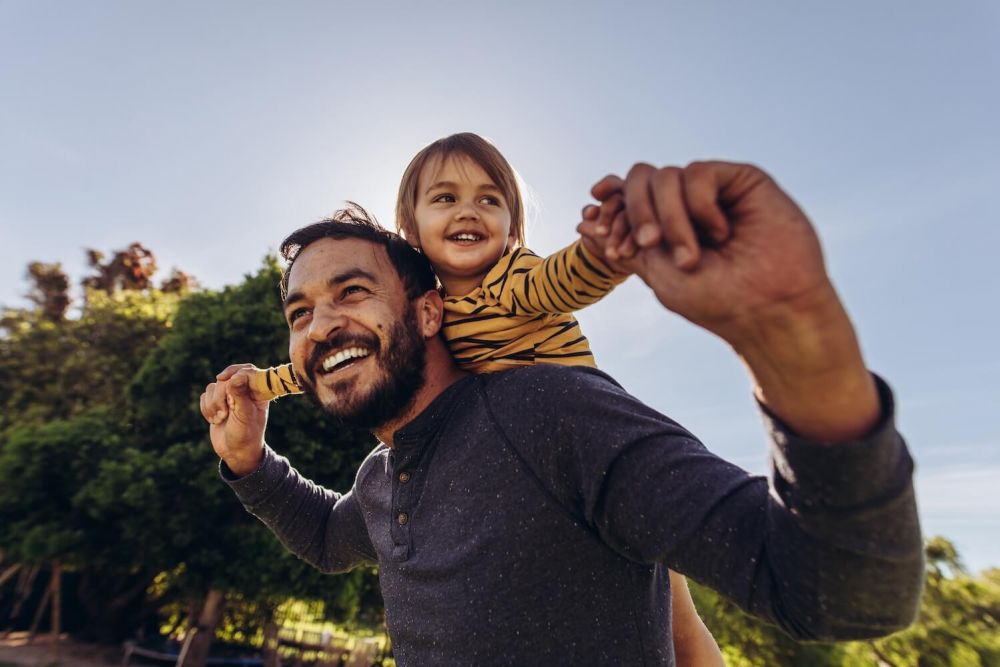 Smiling man playing with his kid outdoors