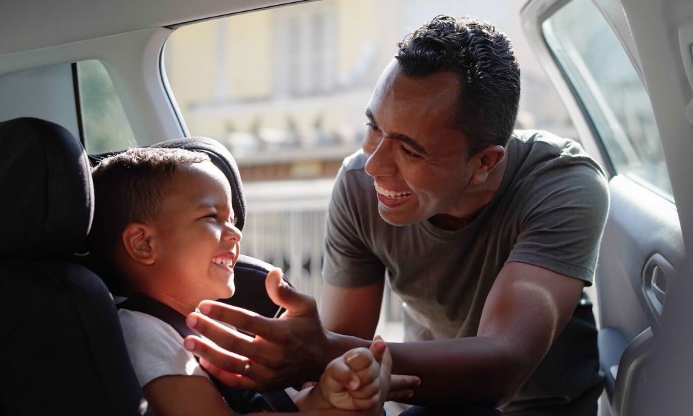 father putting son in car seat