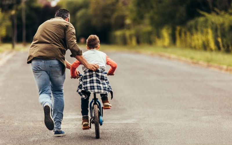 dad teaching child to ride a bike