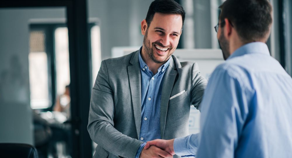 Portrait of cheerful young manager handshake with new employee.