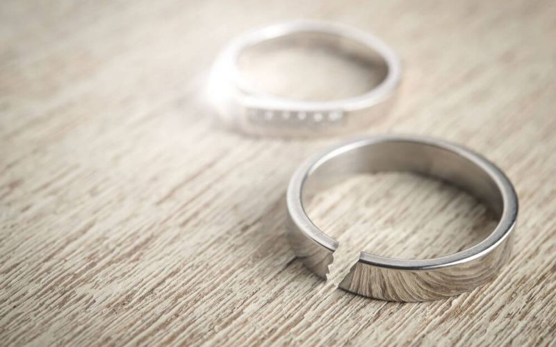 Two rings rest side by side on a textured wooden surface; one is intact and the other is broken in half.