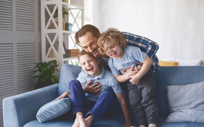 father playing with his kids on couch