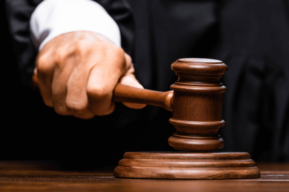A judge in robes holding a gavel at a courtroom bench