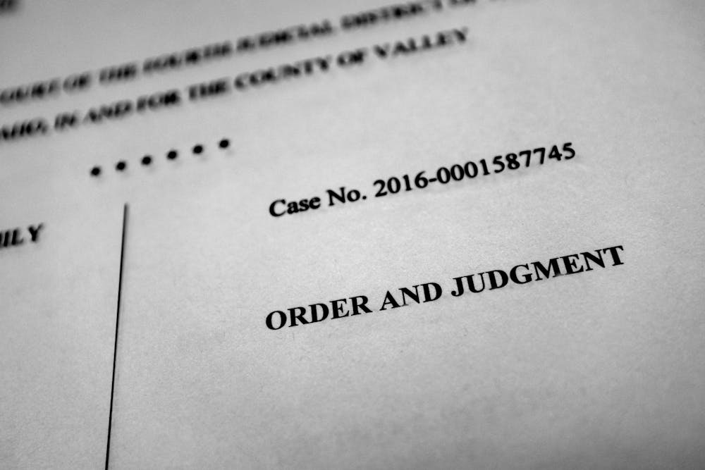 A printed document with the title "ORDER AND JUDGMENT" and "Case No. 2016-0001587745" situated in a nondescript, neutral space.