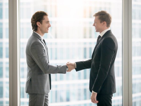 Side view portrait of two smiling business partners making agreement
