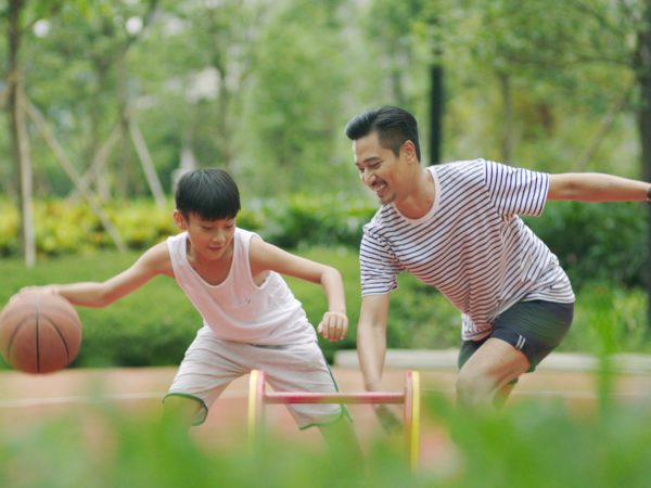 father and son playing basketball in garden