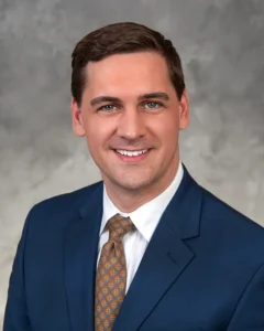 Meade_Thomas - Cordell & Cordell Head-and-shoulders portrait of Thomas Meade in a navy suit, white shirt, and brown patterned tie against a gray backdrop.